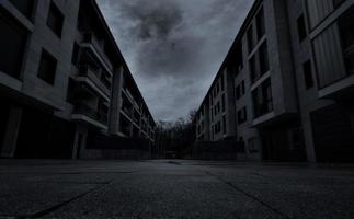 Perspective view of empty road between residential building with dark clouds and sky in the city. No people on urban street. Real estate and property crisis impact of coronavirus or covid-19 concept. photo