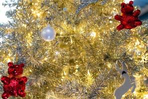 cierra la decoración del árbol de navidad con bolas blancas, renos plateados y osos rojos y luz dorada. fondo de navidad. fondo de navidad y feliz año nuevo. fondo para el tema de la Navidad. foto