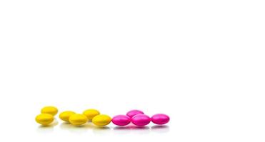 Pile of pink and yellow round sugar coated tablets pills isolated on white background with copy space. Colorful pills for treatment anti-anxiety, antidepressant and migraine headache prophylaxis. photo
