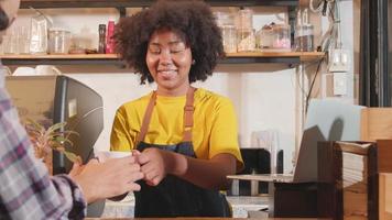 barista de café afroamericana en delantal informal feliz con el pedido de un cliente en línea en una computadora portátil, trabajos alegres con una sonrisa en el mostrador de la cafetería, estilo de vida emprendedor de pequeñas empresas. video