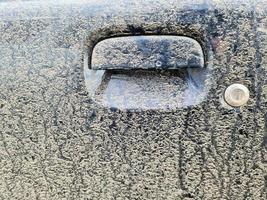 A very dirty car handle at a black car door. photo