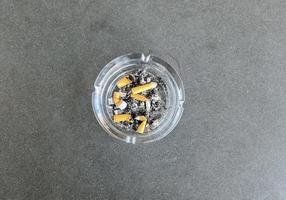 vista superior del cenicero lleno de colillas de cigarrillos. foto