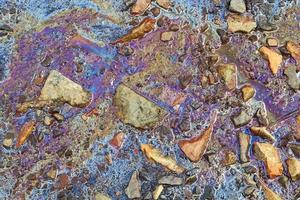 Colorful fuel and oil on an asphalt texture showing heavy enviromental pollution. photo