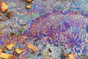 Colorful fuel and oil on an asphalt texture showing heavy enviromental pollution. photo