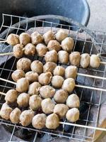 las tradicionales albóndigas de cerdo al estilo tailandés con las brochetas se asan a la parrilla en una rejilla metálica. foto