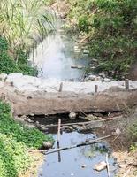 canal de aguas residuales con una pequeña presa de sacos de arena foto