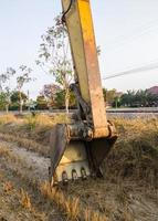 el cubo grande con la garra afilada de la excavadora está tirado en el suelo. foto