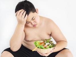 A fat boy hate to eat vegetable salad photo