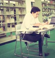 Vintage photo of sitting man is reading and working in a library background