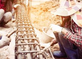 Vintage style photo of construction workers are installing steel rods in reinforced concrete beam