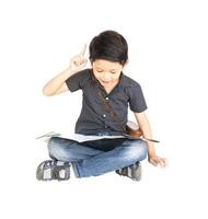 7 years old Asian traveler boy is happily sitting and looking at a map while pointing up his index finger isolated over white photo