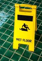 Wet floor caution sign with rain drop on the green tiles floor photo