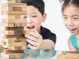 los niños juegan jenga, un juego de torre de bloques de madera para practicar su habilidad física y mental foto