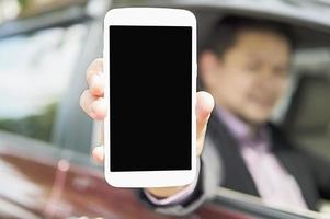 Driver is showing mobile phone with black blank screen while sitting in a car. Photo is focused at mobile screen and includes CLIPPING PATH for mobile screen.