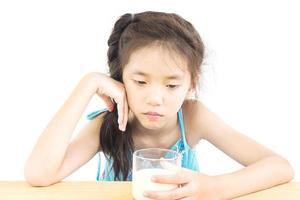 Asian girl is showing dislike drinking milk expression over white background photo