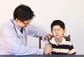 Sick Asian boy being treated by male doctor over white background photo