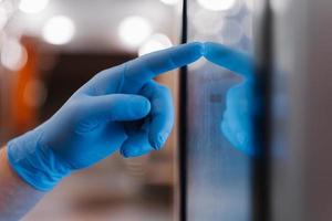 Cropped shot of mans hand in latex medical glove, uses touchscreen, checks information during quarantine pandemic coronavirus, enters pin code on self checkout. Hygiene and virus prevention concept photo