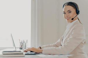 Smiling call center agent in headset consulting client photo