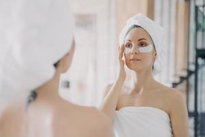 Mirror reflection of girl which applies eye patches and doing skincare. Relaxation at home. photo