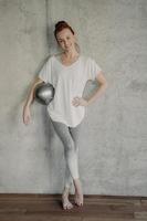 Happy female with small pilates ball resting after workout in studio photo