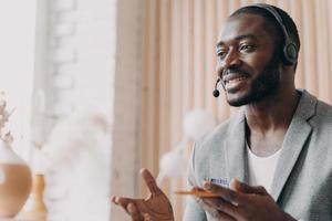 Handsome african american businessman in headset speaking by video call in office photo