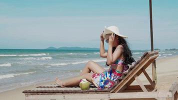 vrouw in bikini liggend op lounge stoel op tropisch strand zon looien vakantie zomer reizen concept video