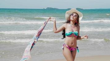 sexy bikini vrouw met sjaal onthulling wandelen op een tropisch strand. concept vrijheid, levensstijl video