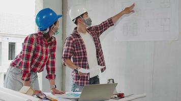 Two Construction worker engineers revising blueprints at construction site video