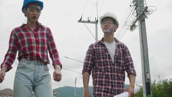 dos ingenieros de construcción asain discutiendo, caminando juntos con el plano video