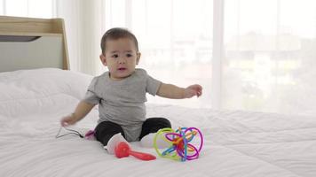 bonito bebé juega al juguete del bebé en la cama. Bebé feliz de 8 meses, cámara lenta video