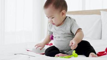 schattig babymeisje geniet met babyspeelgoed op bed video