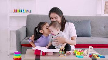 schattige dochter stuurt liefdescadeau naar moeder en kus tijdens het spelen met baby, moederdagconcept video