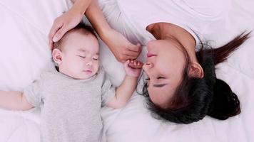 gelukkige familie, jonge moeder zorgt voor haar babymeisje dat op het bed slaapt. slow-motion schot. video
