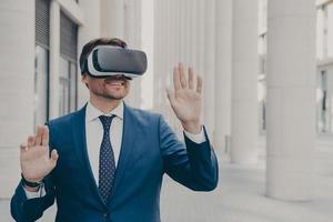 Professional male architect in augmented reality headset gesturing while standing outdoors photo