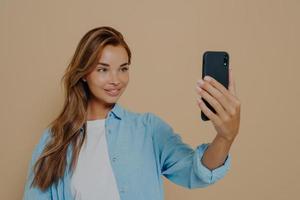 Adorable female model poses for making selfie in studio photo