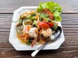 Closeup of the spicy Thai seafood salad served in the white plate. photo