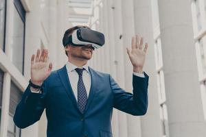 Businessman using VR headset for virtual reality game for work, standing outdoors photo
