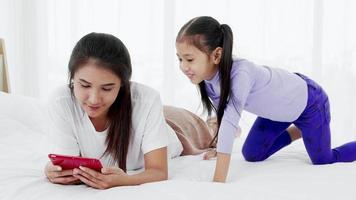 mother and young child lying on bed while playing on tablet in the daytime video