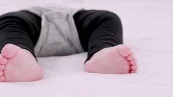 närbild porträtt av baby fötter och en sova på sängen under dagtid, panorera vy video