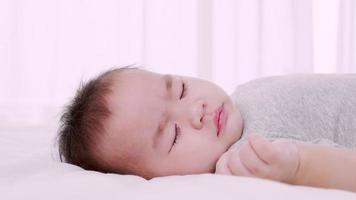 baby sleeping on the bed in the home during the daytime, Close-up shot, Slow motion video