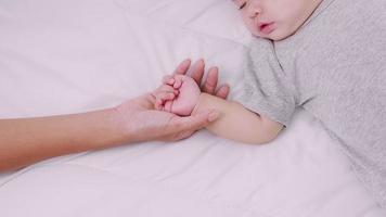 Nahaufnahme über der Mutter, die die Hand ihres Kindes auf dem Bett hält, glückliches Familienneugeborenes video