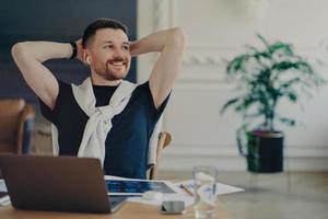 Happy businessman resting after work done at his cozy workplace in modern office photo