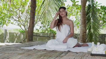 Young beautiful Asian woman sitting on spa bed, preparing to receive neck massage spa video