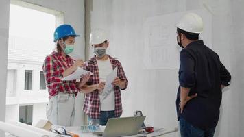 tres ingenieros de construcción asain discutiendo junto con el plano, el dibujo y el diseño video