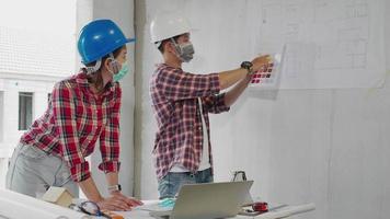 Two civil engineers look blueprint while checking infrastructure in construction site