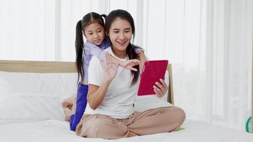 heureuse mère et petite fille s'amusant à faire un appel vidéo technologique avec une tablette numérique video