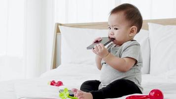 schattige babymeisje spelen met babyspeelgoed en smartphone. slim grappig kind video