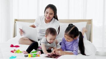 Busy woman caring of her baby and little daughter and working from home with laptop