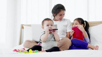 Mother of busy working on laptop computer, playing with baby and talking to little daughter video