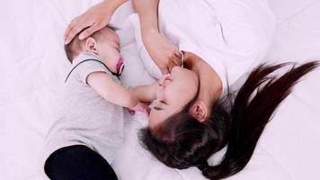 moeder liggend met haar pasgeboren slapende baby in bed met liefde, slow-motion shot. video